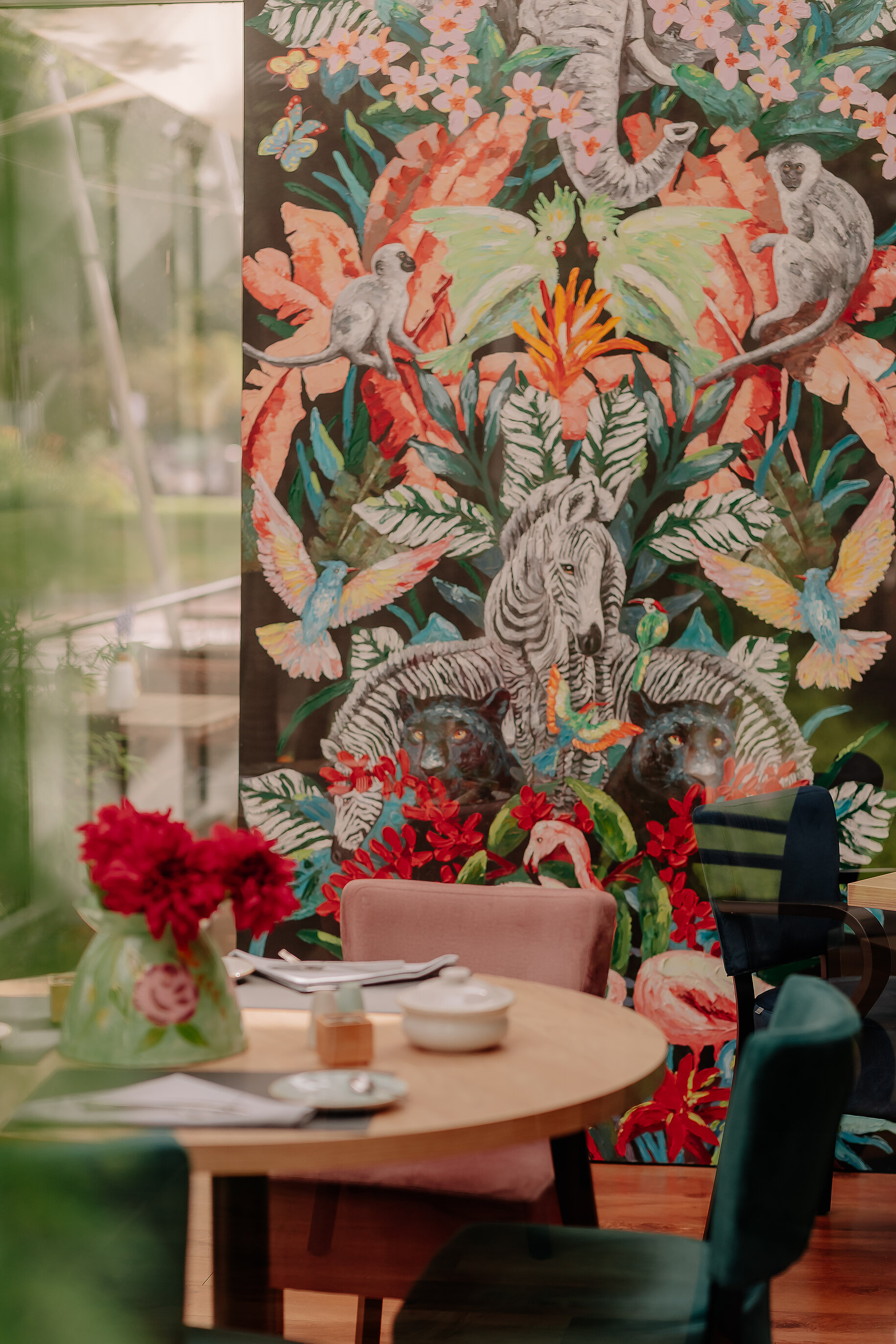 Buntes Wandbild mit Tiermotiven hinter einem Frühstückstisch im Wintergarten des Stadthotels Borken