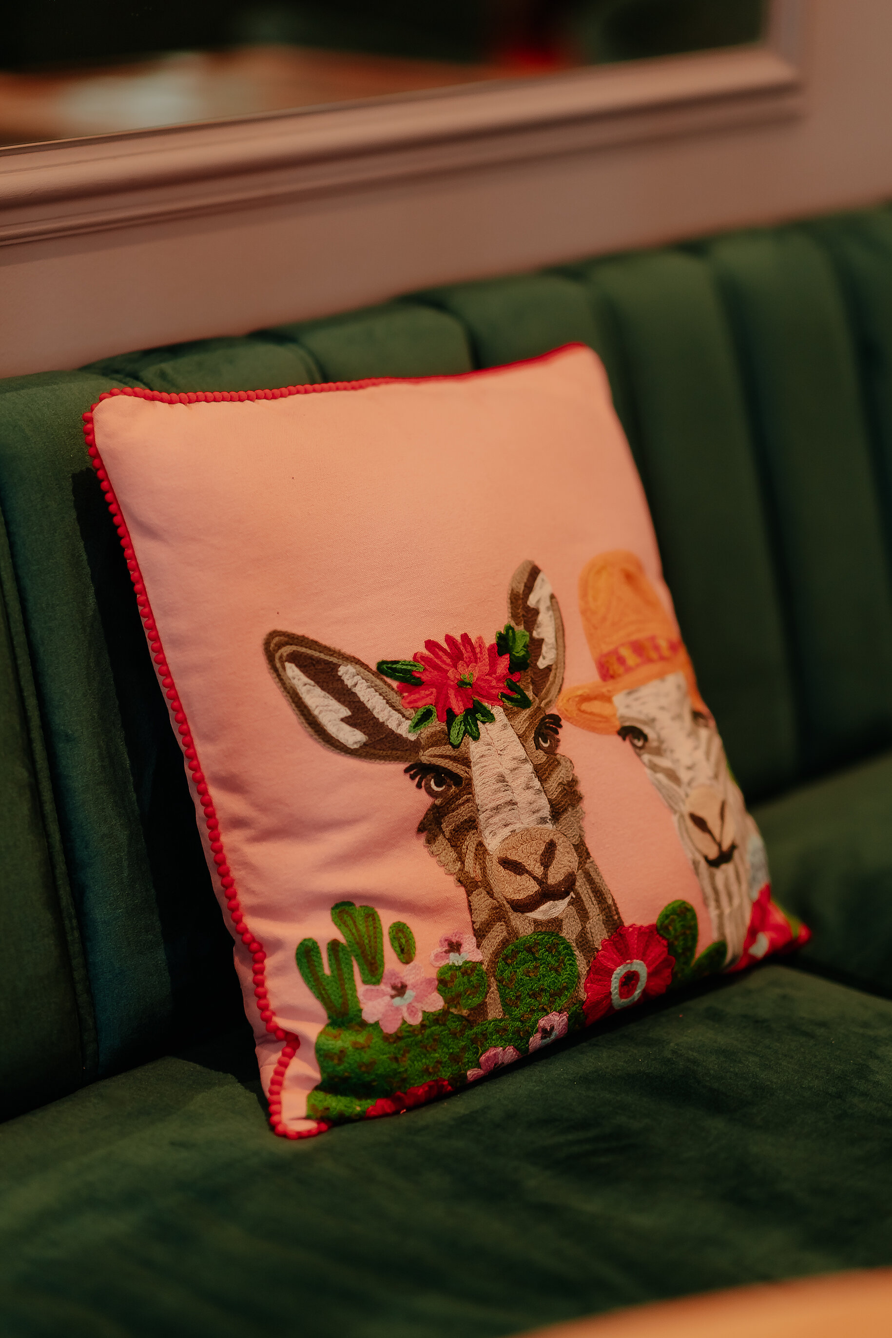Detailaufnahme eines pinken Zierkissens mit Lamas auf einem grünen Sofa im Stadthotel Borken